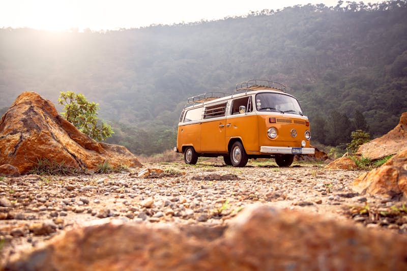 Camping-car garé face à un paysage de montagne avec un couple préparant le petit-déjeuner en extérieur