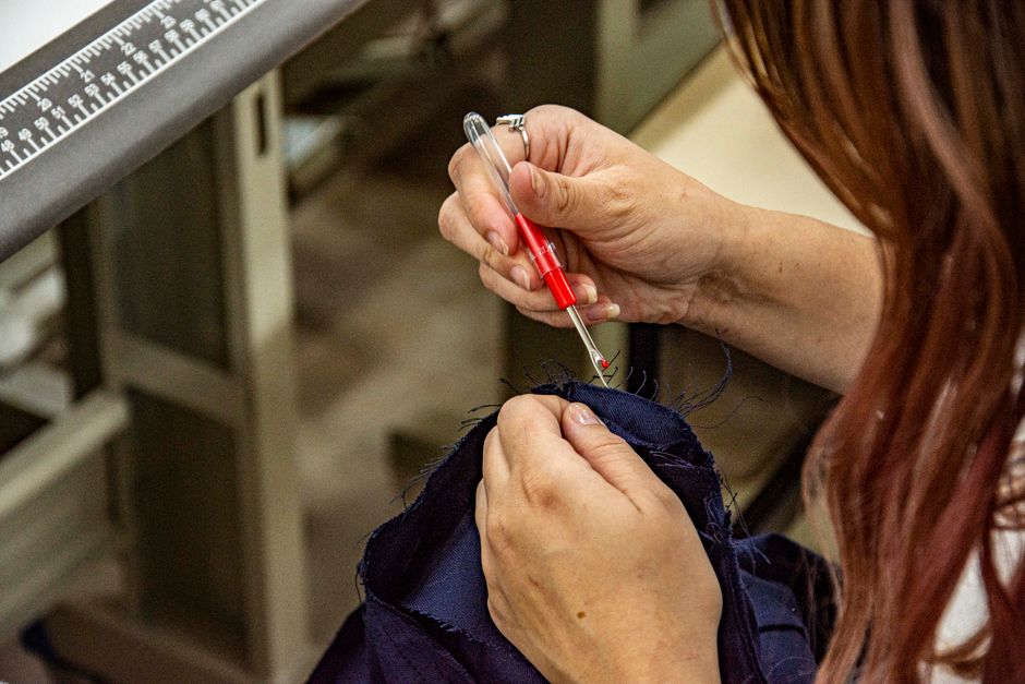 Découd-vite et petits ciseaux de couture posés sur un tissu de manteau gris clair, montrant les outils essentiels pour découture textile
